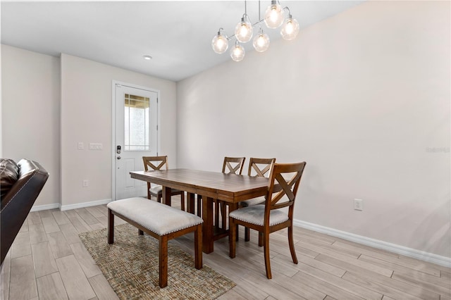 dining area with light wood-type flooring and an inviting chandelier