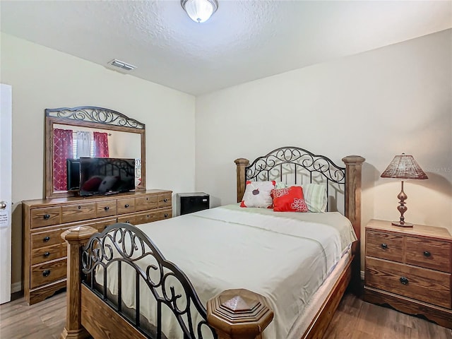 bedroom with wood-type flooring and a textured ceiling