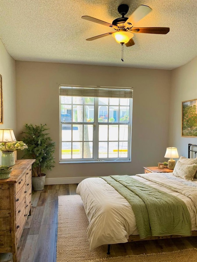 bedroom with dark hardwood / wood-style flooring, a textured ceiling, multiple windows, and ceiling fan