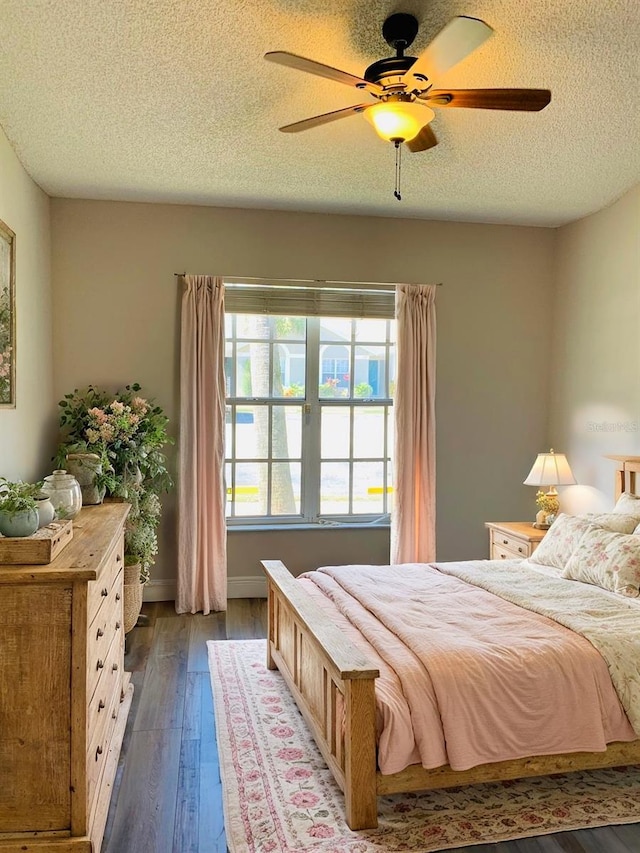 bedroom with a textured ceiling, wood-type flooring, and ceiling fan