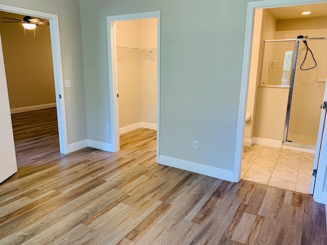 unfurnished bedroom featuring a closet, a walk in closet, and light wood-type flooring