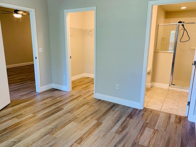 unfurnished bedroom with baseboards, wood finished floors, a walk in closet, and a closet