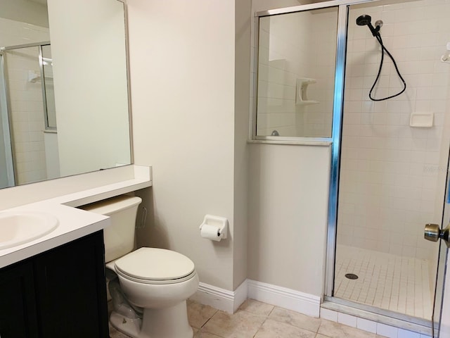 bathroom featuring tile patterned flooring, a shower stall, toilet, vanity, and baseboards