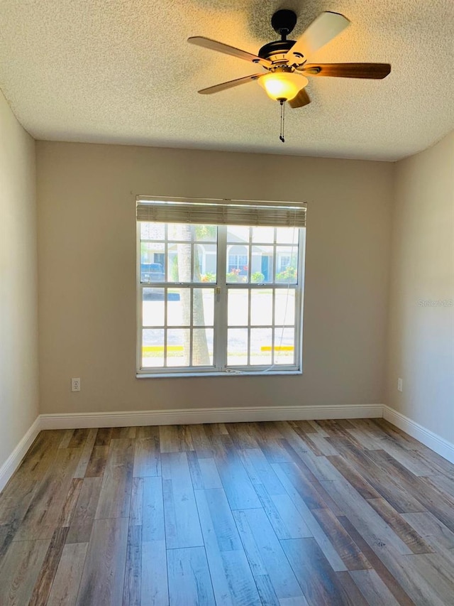 empty room with a textured ceiling, wood-type flooring, and ceiling fan