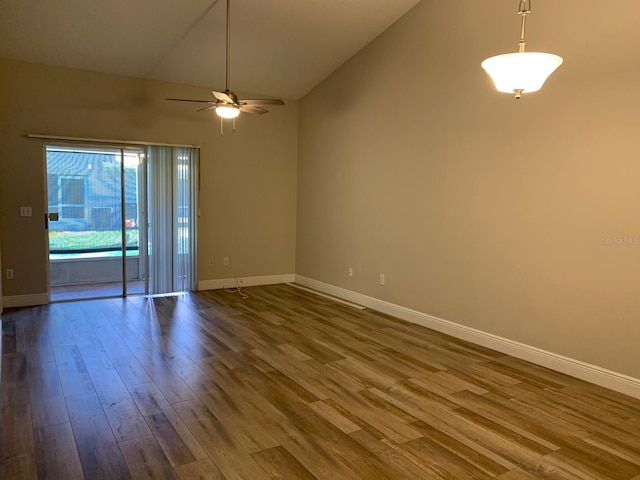empty room featuring vaulted ceiling, a ceiling fan, dark wood finished floors, and baseboards