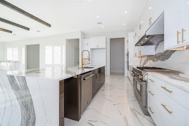 kitchen with light stone counters, white cabinets, sink, a large island, and appliances with stainless steel finishes