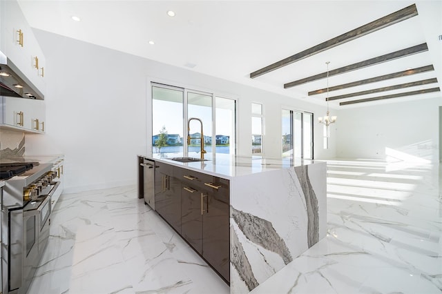 kitchen featuring beam ceiling, decorative light fixtures, a notable chandelier, light stone counters, and stainless steel appliances