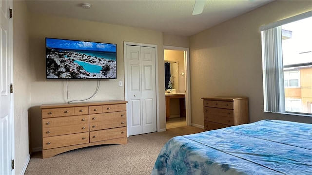 bedroom featuring connected bathroom, light carpet, ceiling fan, and a closet