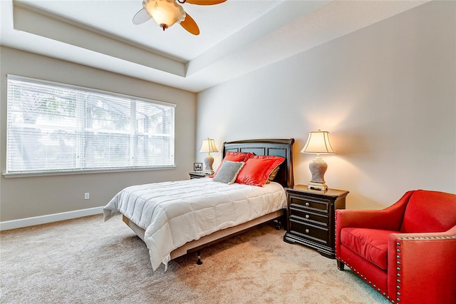 bedroom with a tray ceiling, carpet, and ceiling fan