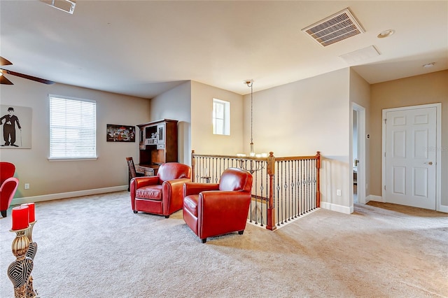 living area with ceiling fan with notable chandelier and light carpet