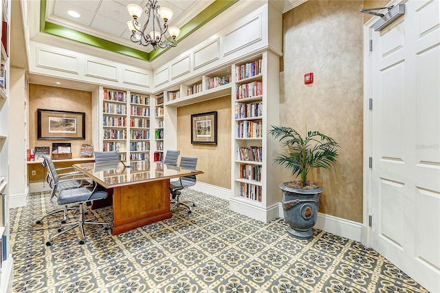 office space with ornamental molding, a tray ceiling, built in shelves, and an inviting chandelier