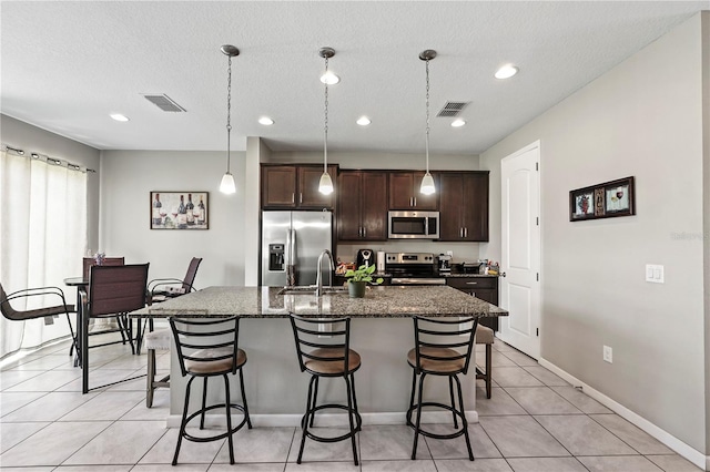 kitchen featuring appliances with stainless steel finishes, a kitchen breakfast bar, light tile patterned flooring, and a center island with sink