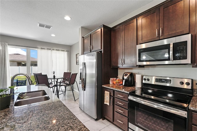 kitchen featuring sink, stainless steel appliances, dark stone counters, and a textured ceiling