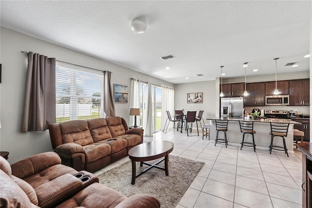 tiled living room with sink and a textured ceiling