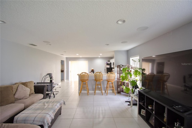 living room with bar, a textured ceiling, and light tile patterned flooring