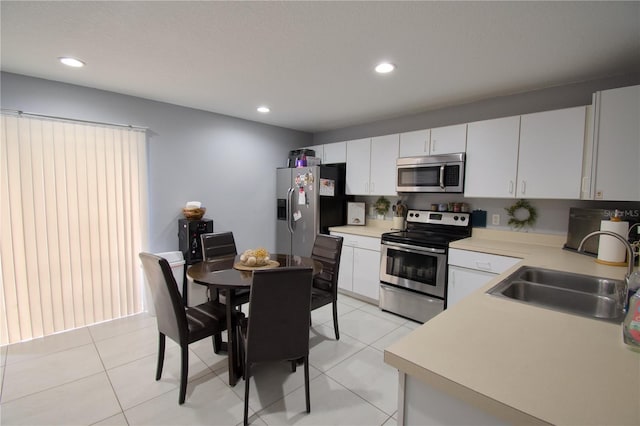 kitchen with white cabinets, stainless steel appliances, sink, and light tile patterned floors