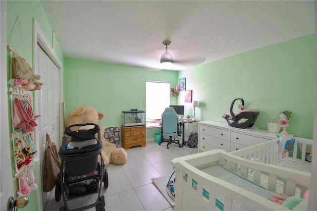 bedroom with a closet, a textured ceiling, a crib, and ceiling fan