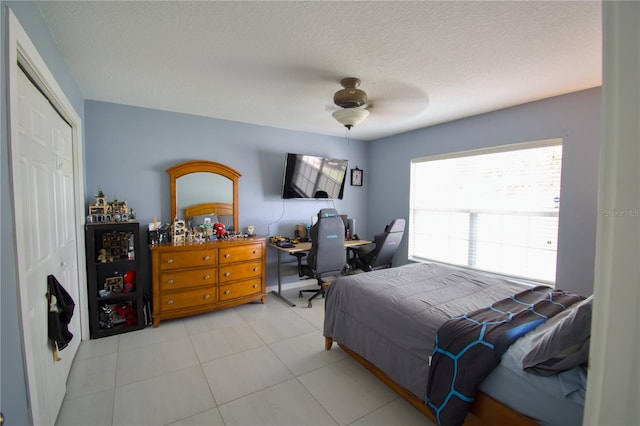 bedroom with light tile patterned flooring, a textured ceiling, a closet, and ceiling fan