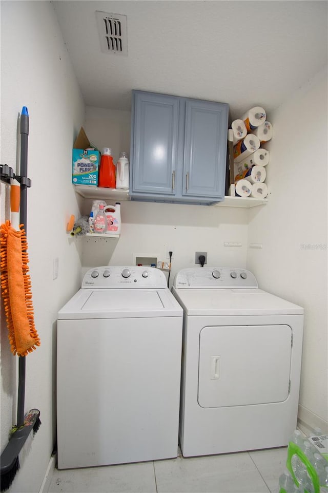 washroom featuring cabinets, washing machine and dryer, and light tile patterned floors