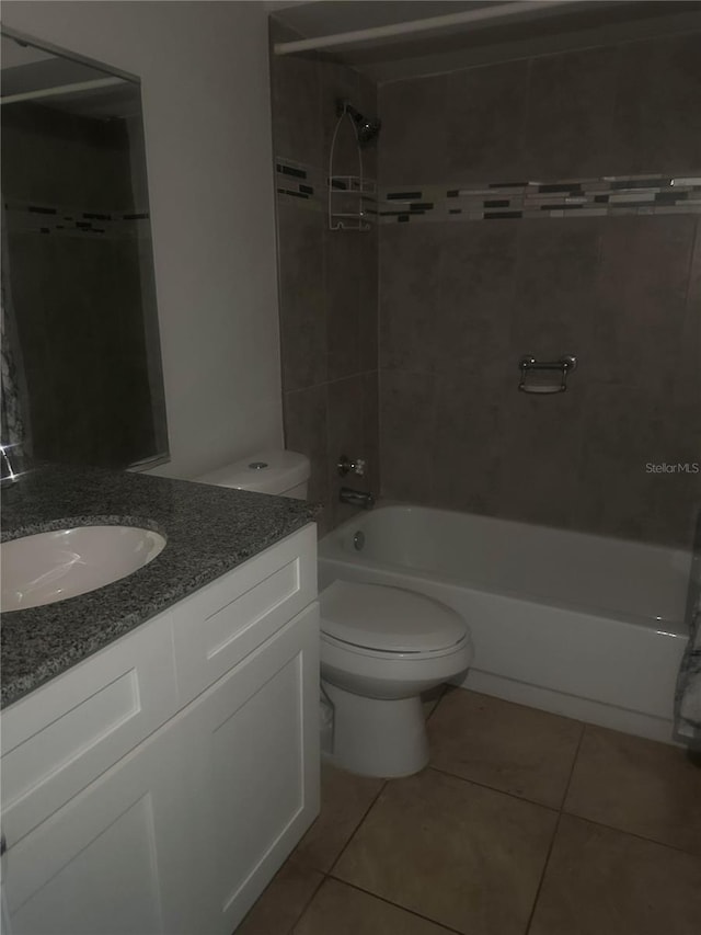 full bathroom with tile patterned flooring, tiled shower / bath, vanity, and toilet