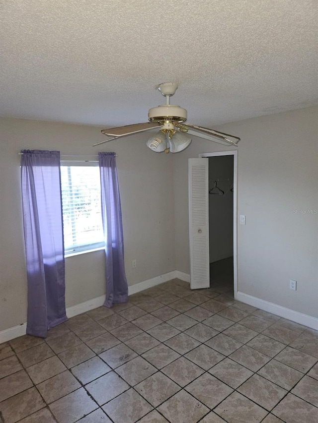 unfurnished room with ceiling fan, a textured ceiling, and light tile patterned floors