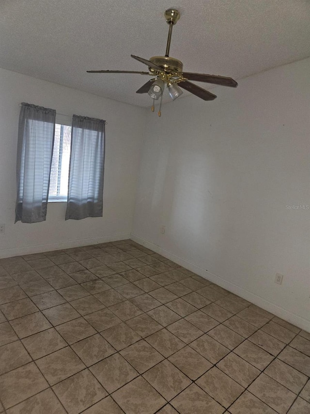 spare room with a textured ceiling, light tile patterned flooring, and ceiling fan