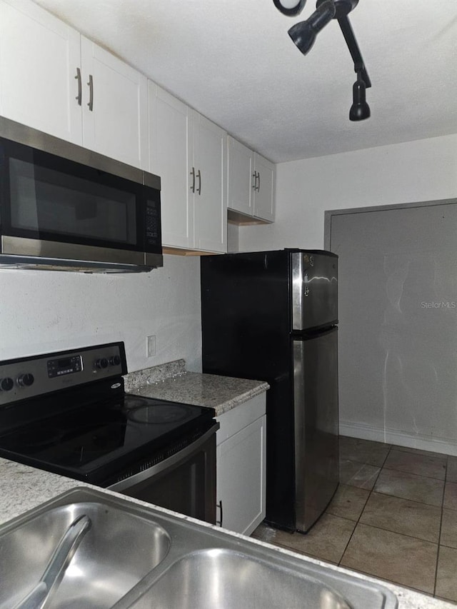 kitchen featuring tile patterned flooring, white cabinets, black appliances, and sink