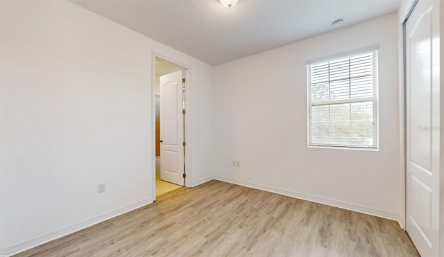 unfurnished room with a textured ceiling and light hardwood / wood-style floors