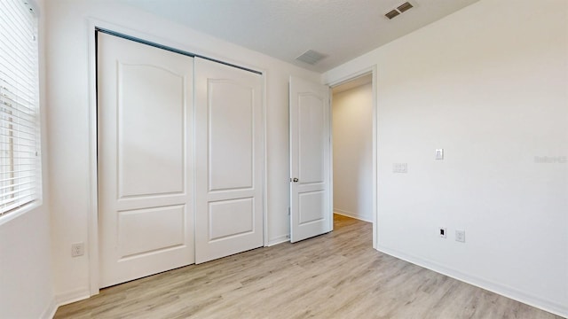 unfurnished bedroom with light hardwood / wood-style floors, a closet, and a textured ceiling