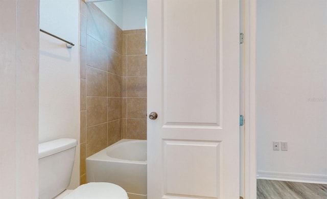 bathroom featuring tiled shower / bath combo, wood-type flooring, and toilet