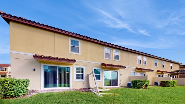 rear view of house featuring central AC unit and a lawn