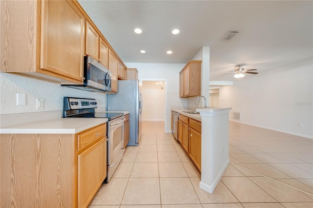 kitchen with ceiling fan, stainless steel appliances, sink, light tile patterned flooring, and a textured ceiling