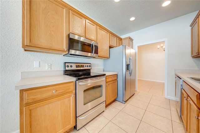 kitchen with appliances with stainless steel finishes, light tile patterned floors, and a textured ceiling