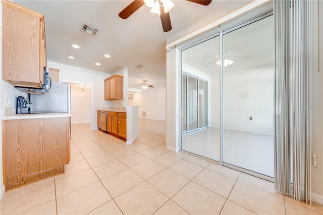 kitchen featuring stainless steel dishwasher, sink, light brown cabinetry, light tile patterned floors, and a textured ceiling