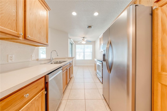 kitchen with ceiling fan, stainless steel appliances, sink, light tile patterned floors, and a textured ceiling