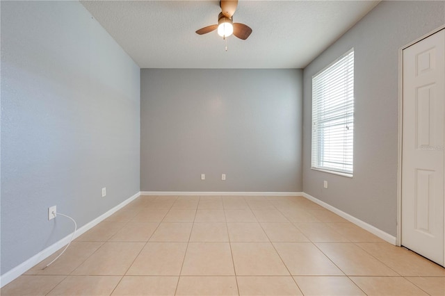 spare room with ceiling fan, light tile patterned floors, and a textured ceiling