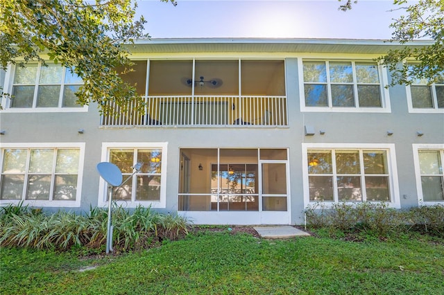 back of property featuring a balcony and a lawn