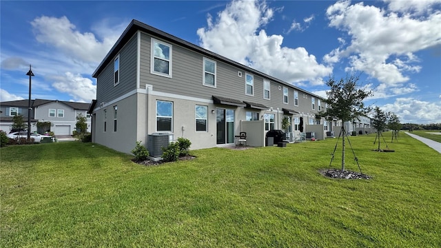 rear view of house featuring a yard, a garage, and central AC