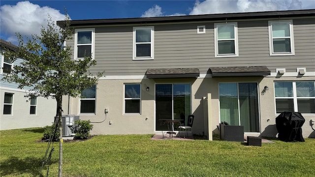 rear view of property featuring a lawn and central AC