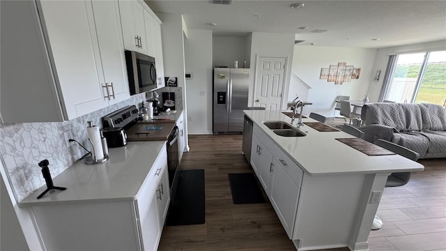 kitchen with white cabinets, sink, a kitchen island with sink, appliances with stainless steel finishes, and dark hardwood / wood-style floors