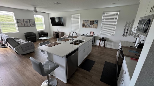 kitchen featuring an island with sink, sink, white cabinetry, stainless steel appliances, and dark hardwood / wood-style floors