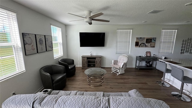 living room featuring ceiling fan, a textured ceiling, and dark hardwood / wood-style flooring