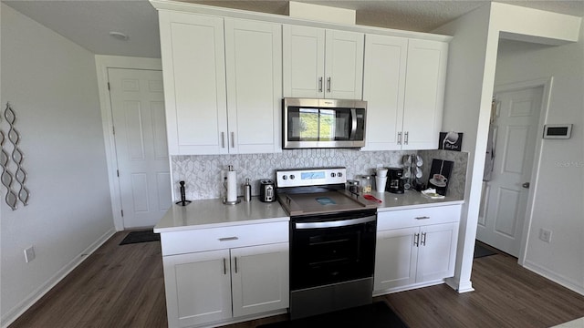 kitchen with decorative backsplash, white cabinetry, appliances with stainless steel finishes, and dark wood-type flooring