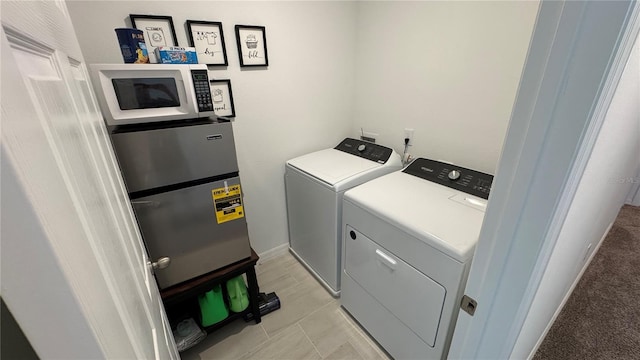 clothes washing area with light tile patterned floors and washer and clothes dryer