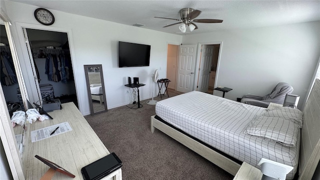 carpeted bedroom with ceiling fan, a walk in closet, and a closet