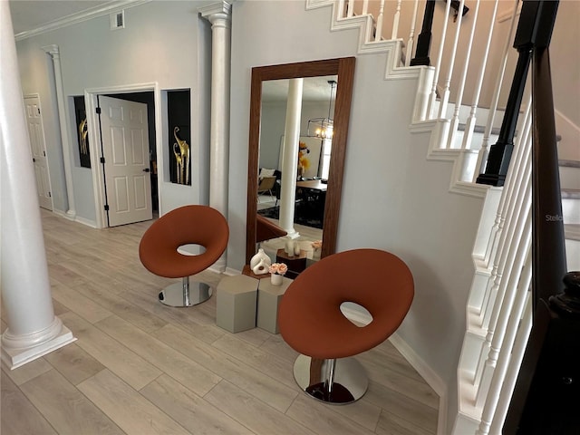 interior space with ornate columns, ornamental molding, light hardwood / wood-style flooring, and a notable chandelier