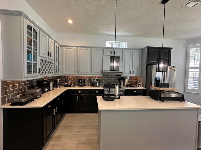 kitchen with light hardwood / wood-style flooring, tasteful backsplash, pendant lighting, and stainless steel range