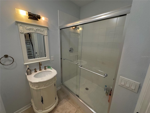 bathroom featuring a shower with door and vanity