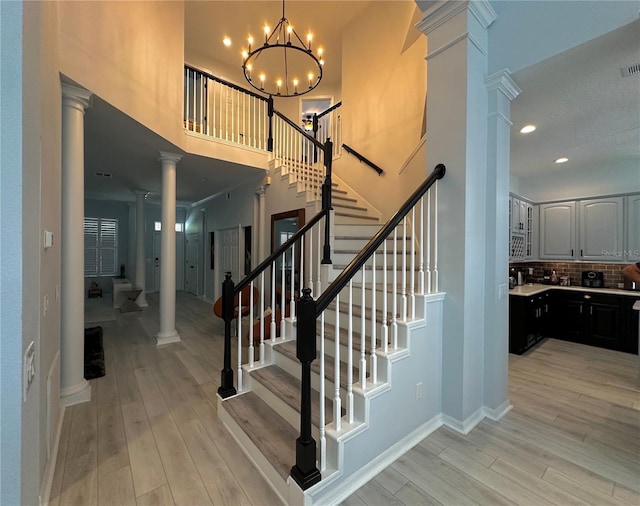 staircase featuring hardwood / wood-style flooring and ornate columns