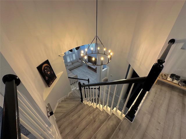 stairway with a high ceiling, an inviting chandelier, and hardwood / wood-style flooring